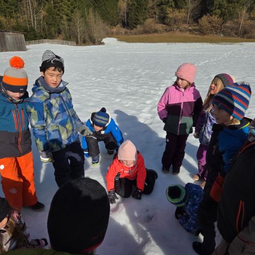Kinder entdecken eine Tierspur im Schnee